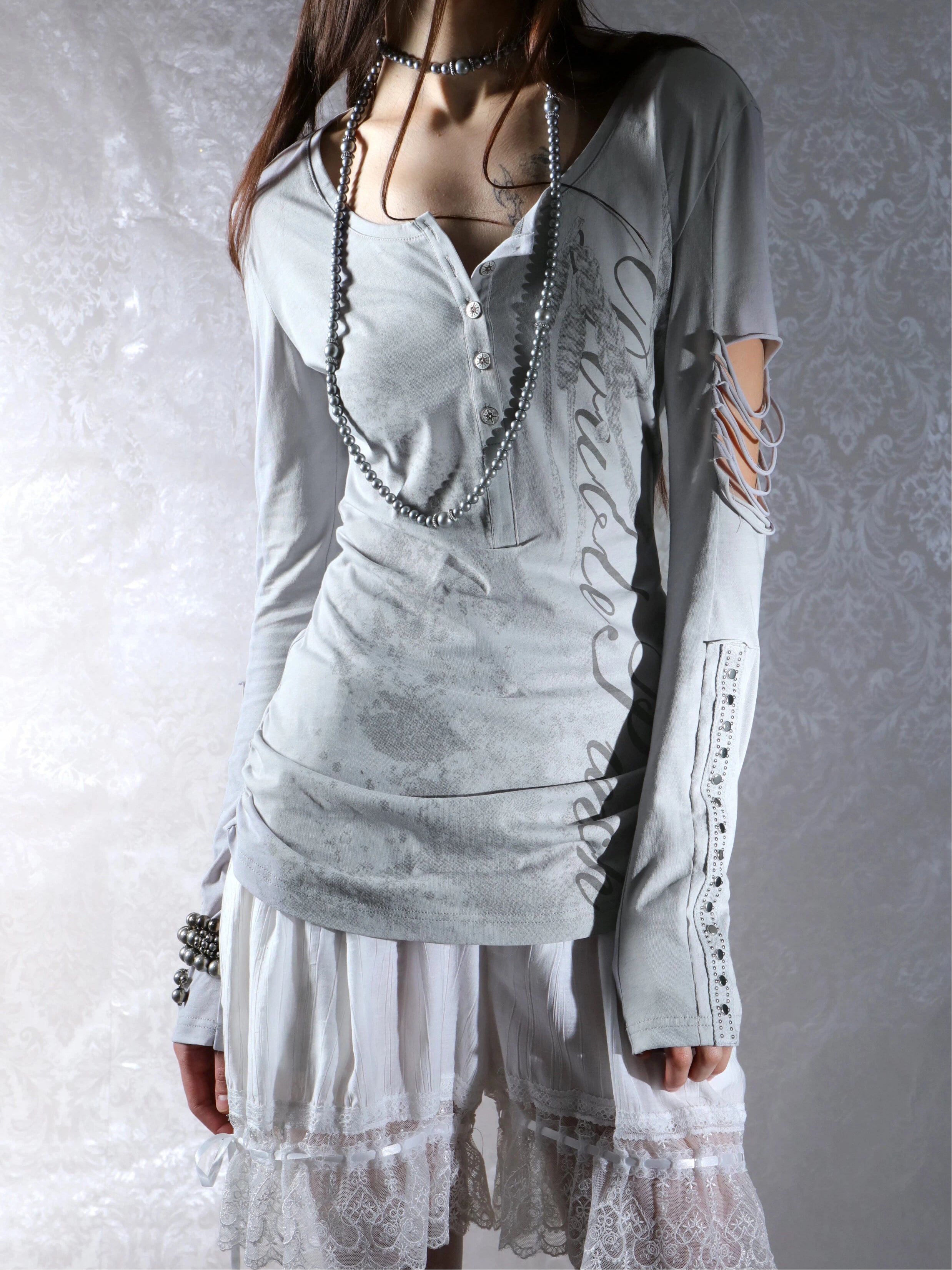 Long sleeve Henley top in mist blue from the Double Punch SS26 'Illusory Glory' collection featuring a distressed graphic print, silver-tone buttons, a cutout sleeve, and studded forearm panels.